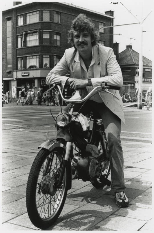 Harry Klorkestein op een Puch bij de Haagse markt, kruising Hoefkade De Heemstraat. Maker onbekend