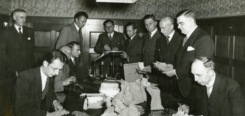 Geldtelling bij het 'Haags crisis comité' op de bank van Heldring en Pierson, Korte Vijverberg 2, 1934. Fotograaf: Gompers. Collectie Haags Gemeentearchief Geldtelling bij het 'Haags crisis comité' op de bank van Heldring en Pierson, Korte Vijverberg 2, 1934. Fotograaf: Gompers. Collectie Haags Gemeentearchief