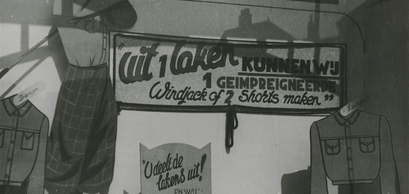 1944, Spui 258-264, Firma Van der Stigchel: 'Uit 1 laken kunnen wij 1 geïmpregneerde windjack of 2 shorts maken' | fotograaf: M. Huizinga 1944, Spui 258-264, Firma Van der Stigchel: 'Uit 1 laken kunnen wij 1 geïmpregneerde windjack of 2 shorts maken' | fotograaf: M. Huizinga